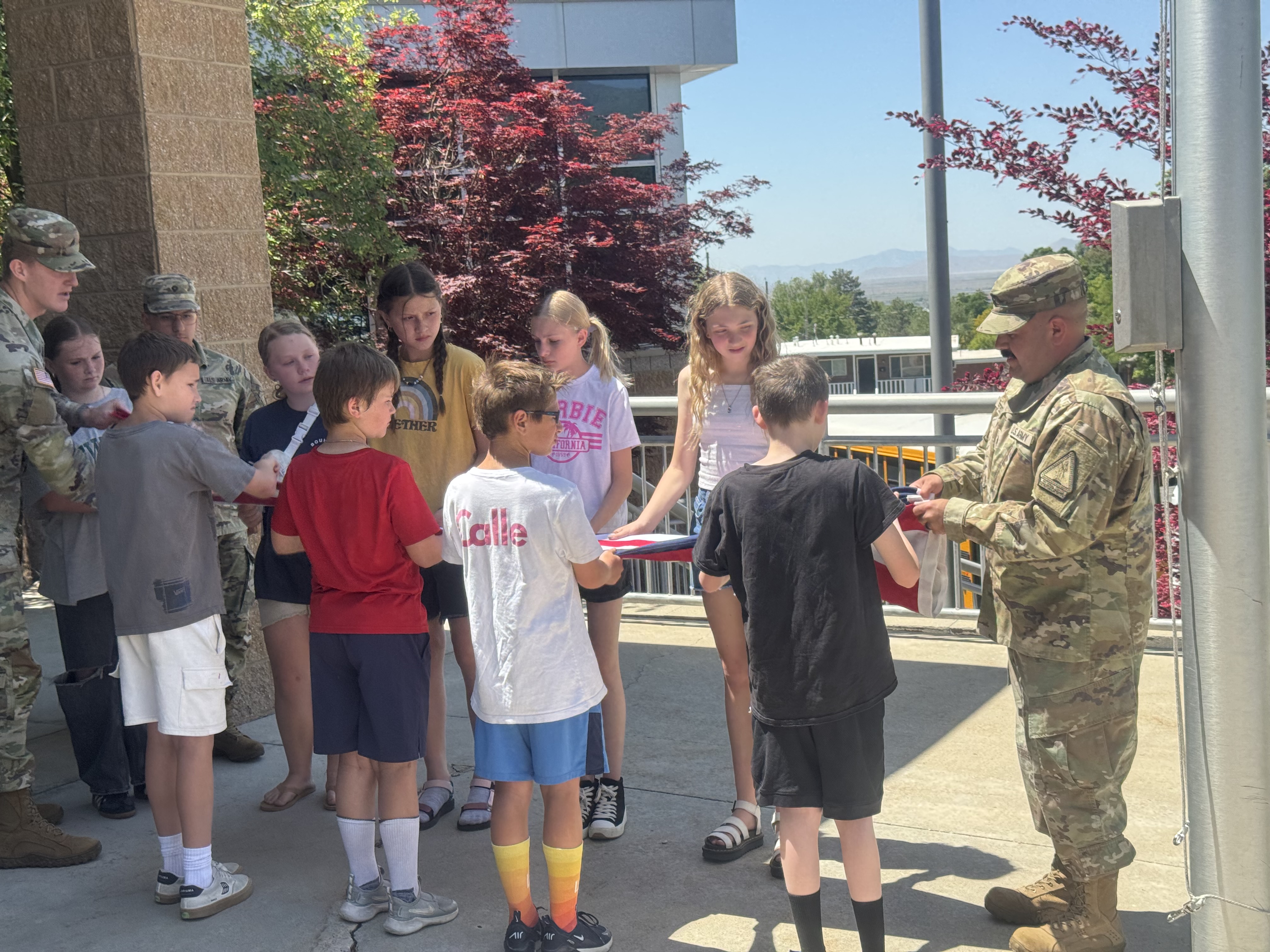 Students folding American flag with the help of the National Guard.
