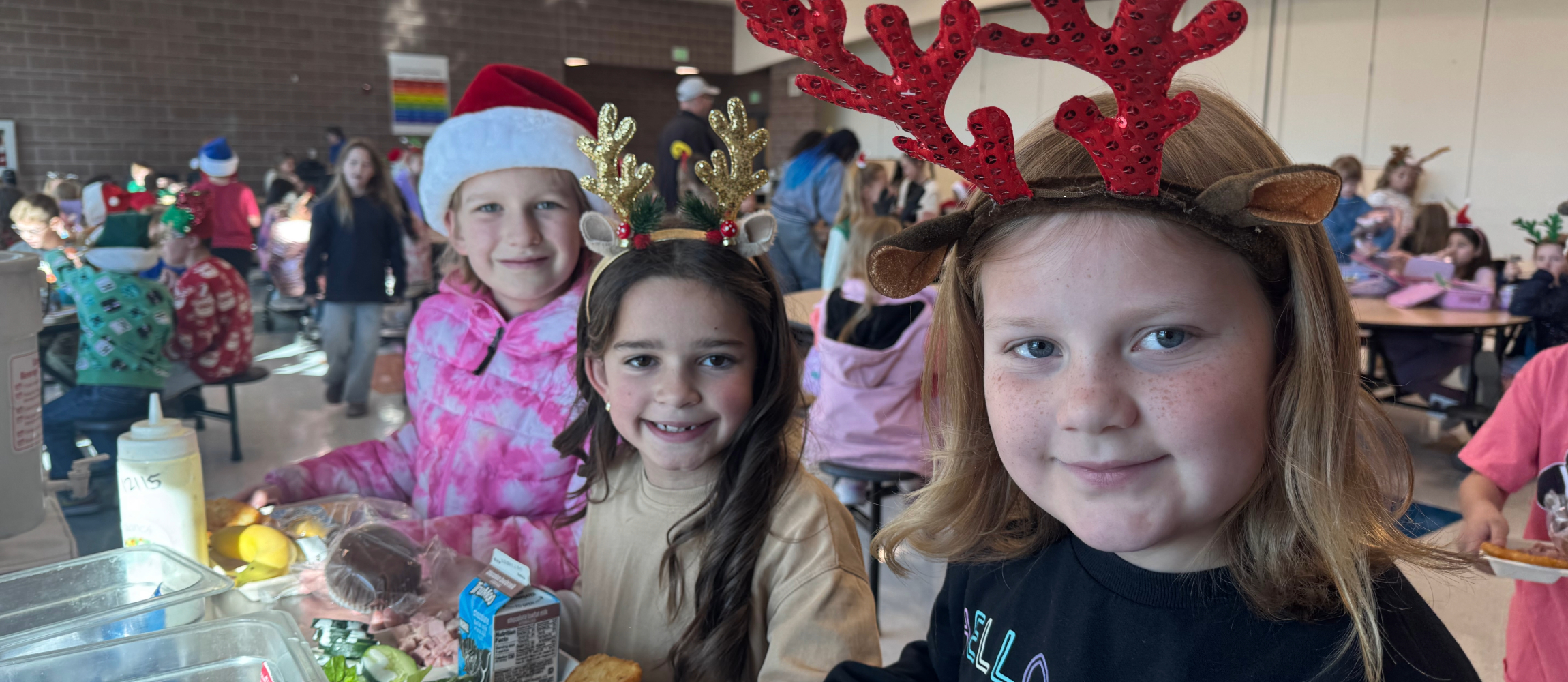 three students in festive hats at lunch
