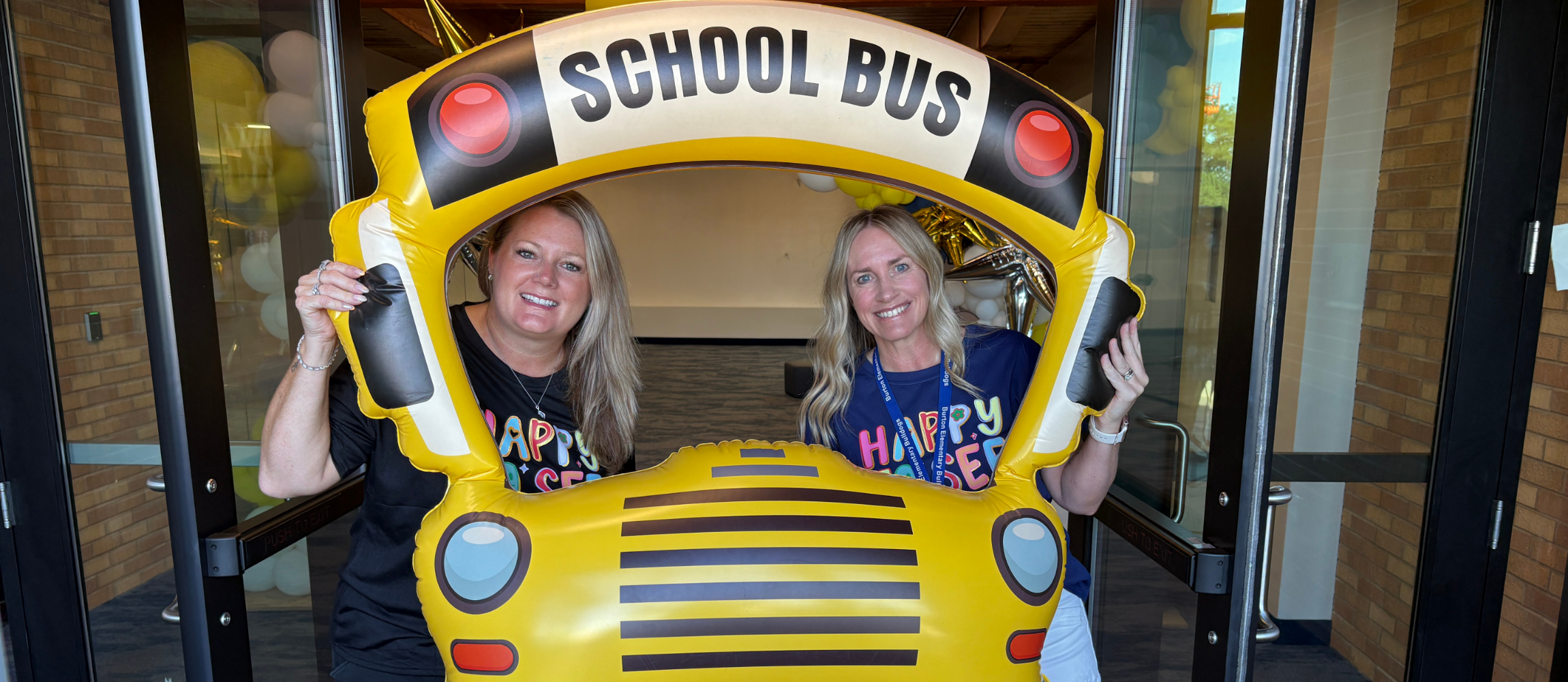 Mrs. Robinson and Mrs. Malan pose in a school bus picture frame