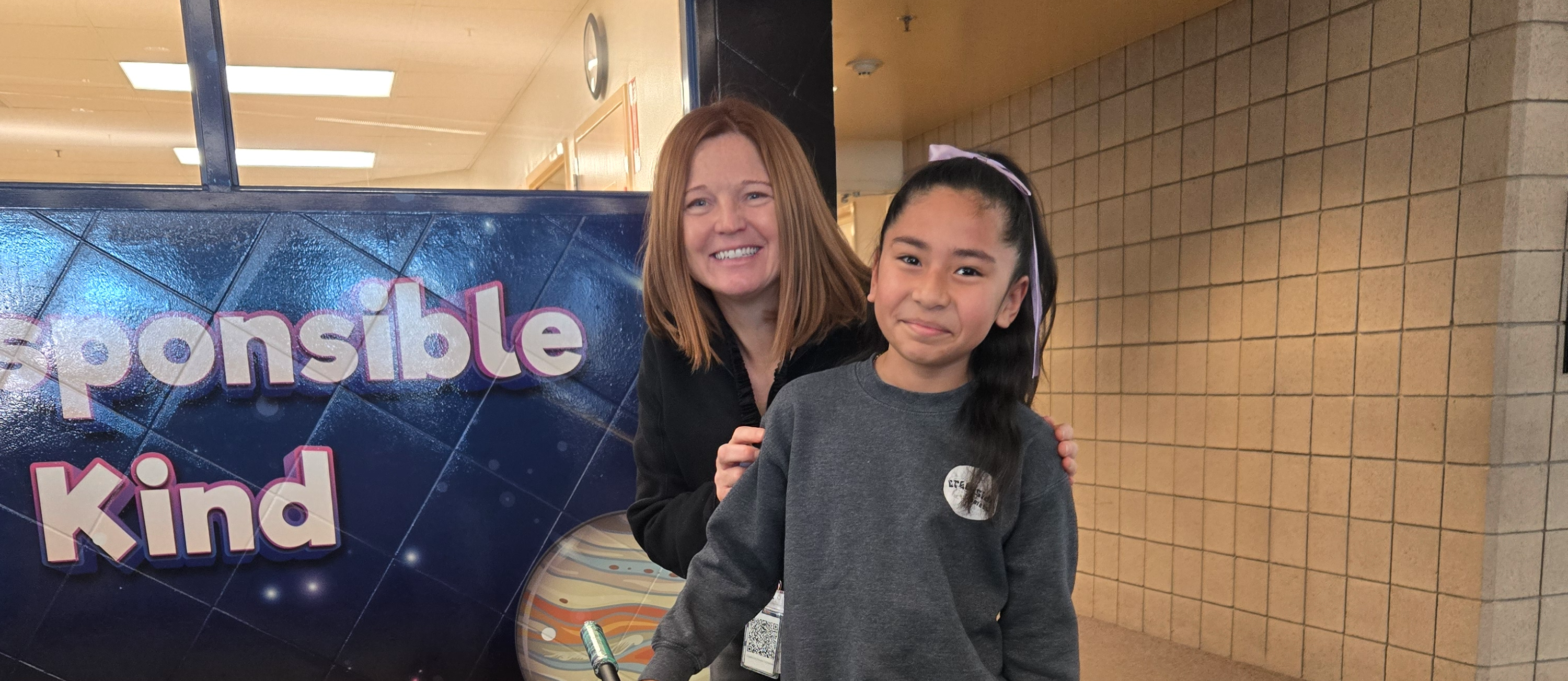 second term scooter winner standing with principal and new scooter