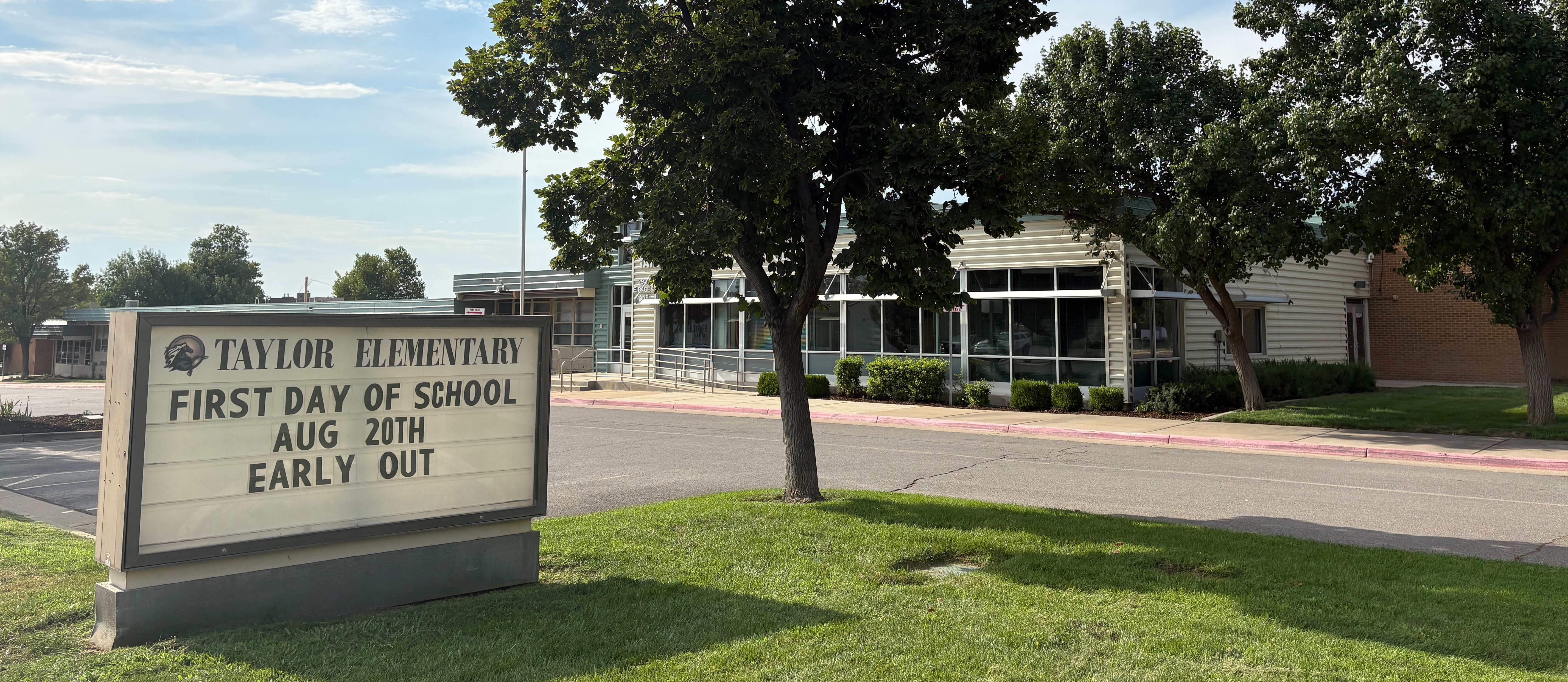 exterior side view of building with "first day of school August 20 early out" on sign