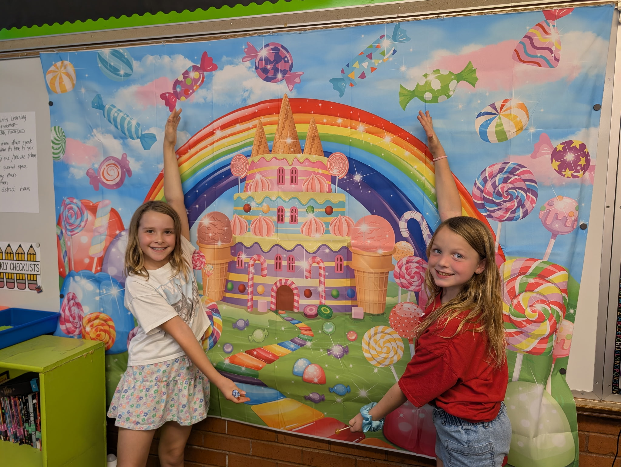 2 girls in front of a candyland poster