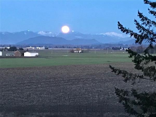 A scenic photo of a farmland with the sunrise on the mountain horizon