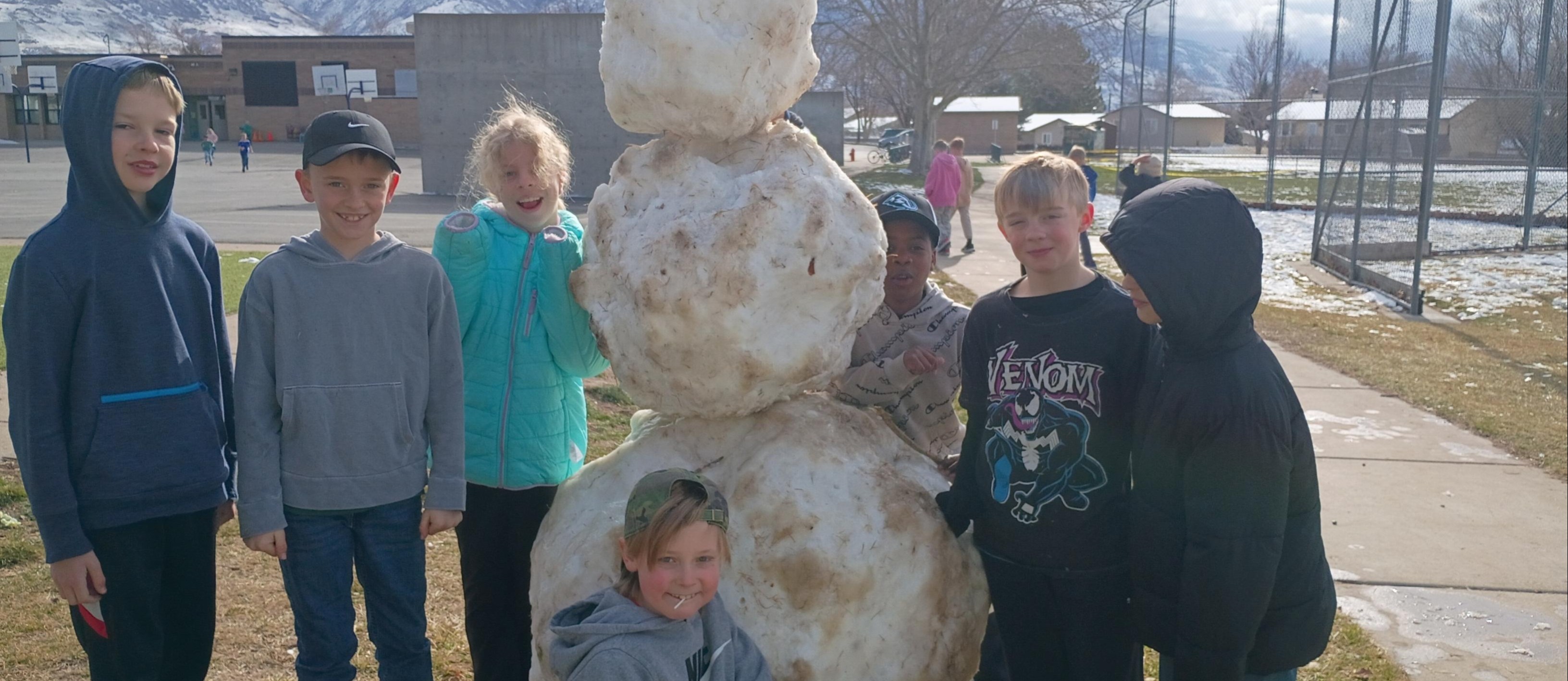 Kids standing next to a snowman