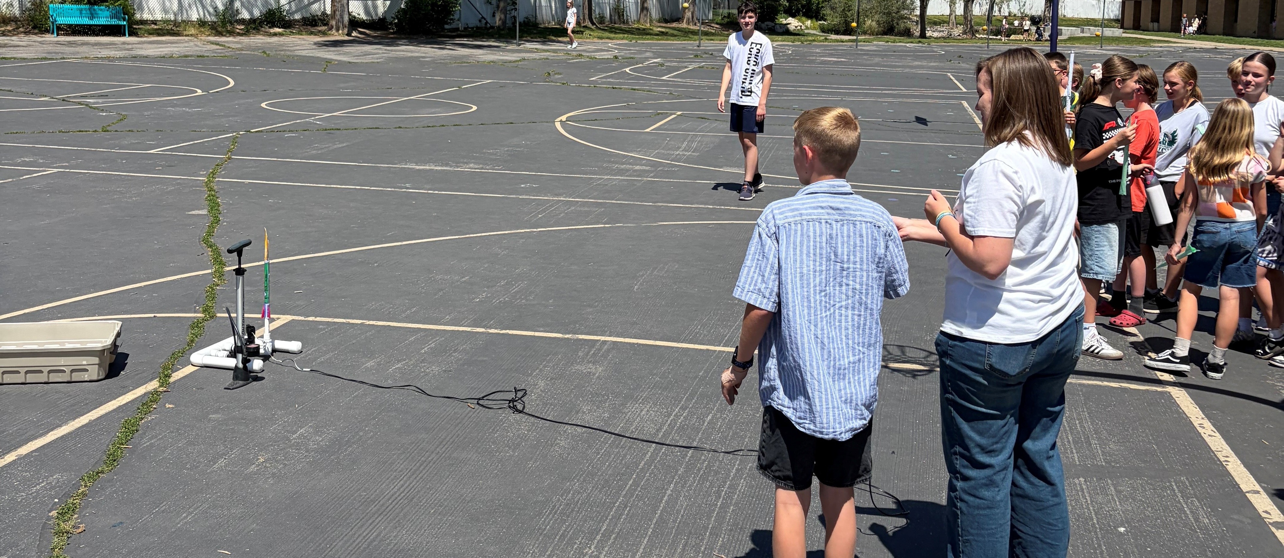 Kids and teacher shooting paper rockets on a playground