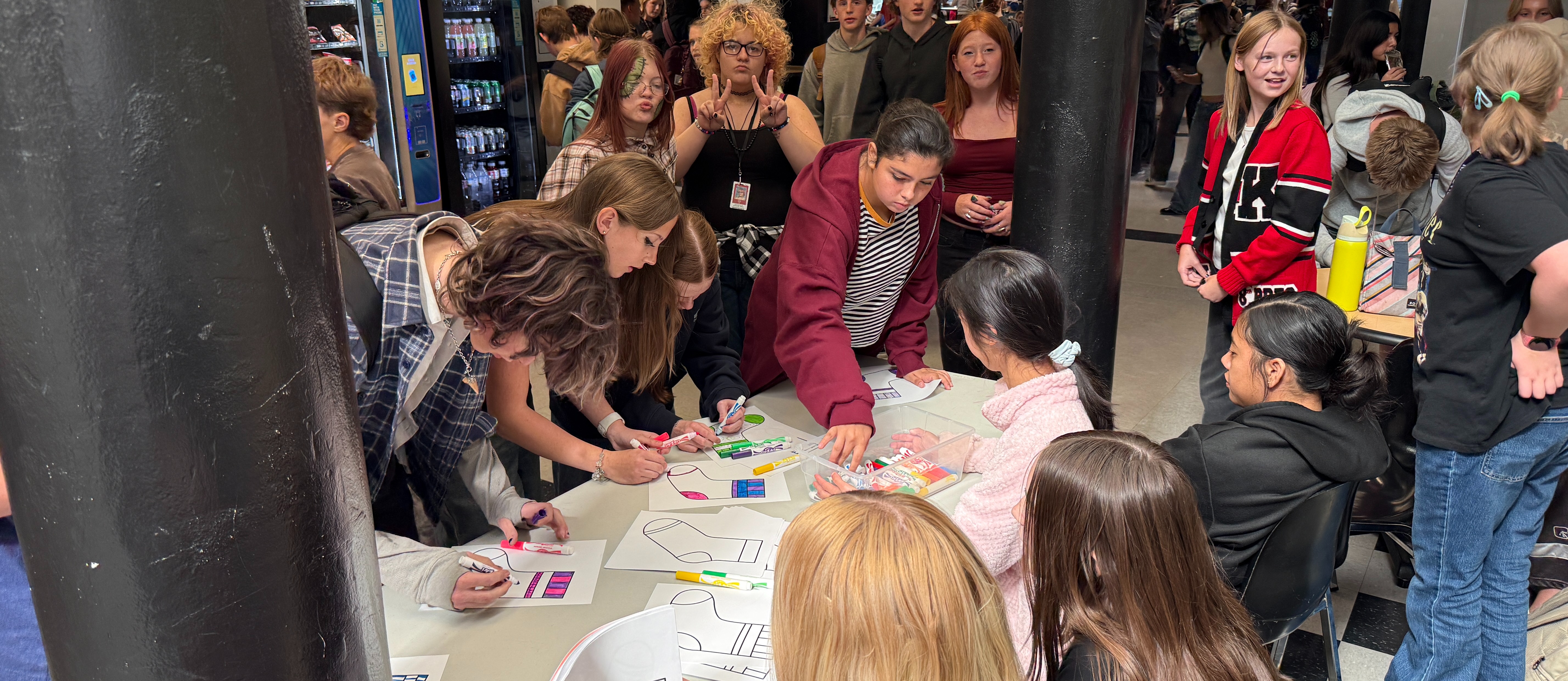 image of students coloring socks, some students are sitting at a table, some students are standing