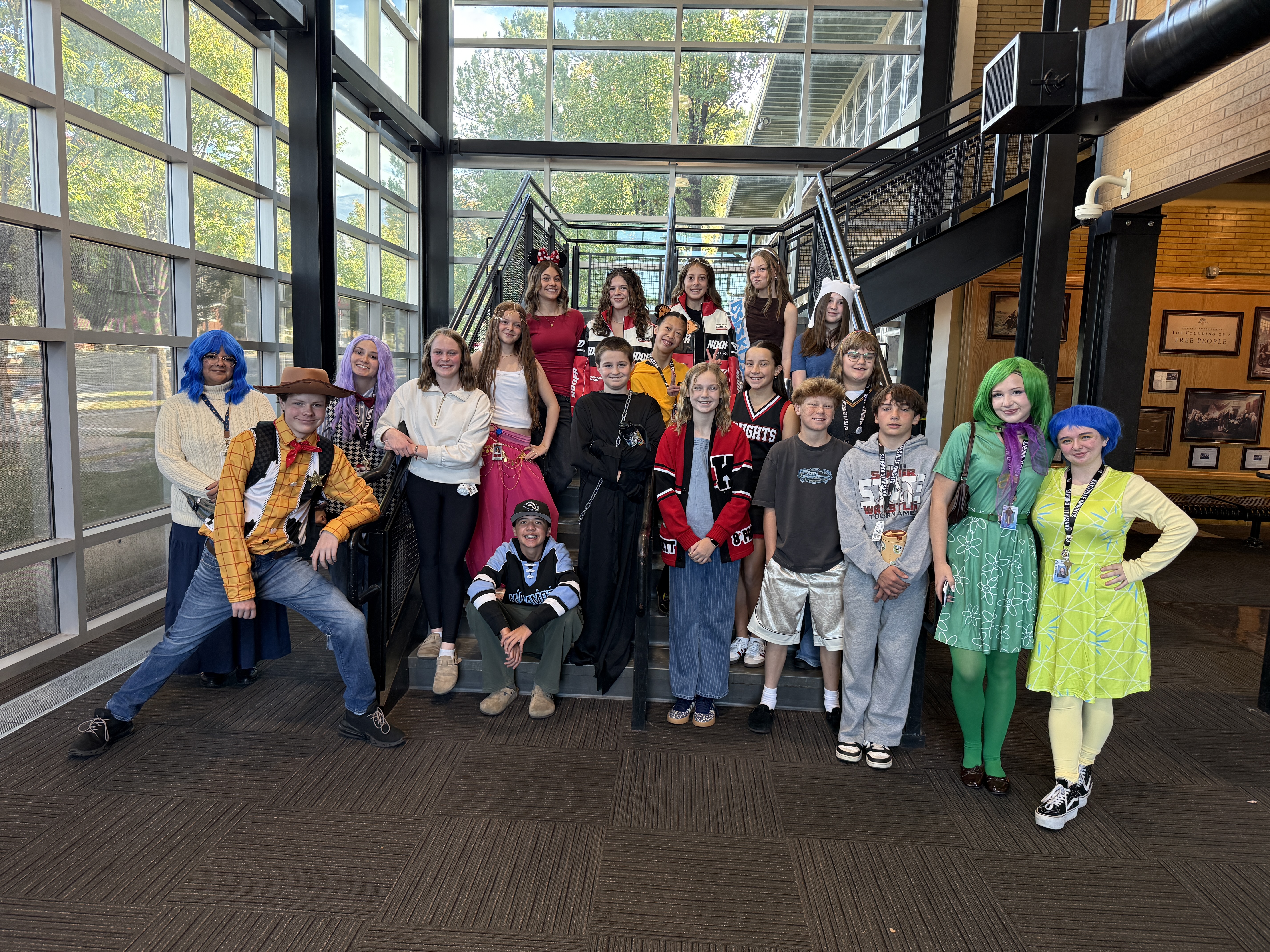 image of students and teachers standing on stairs, some are in Halloween costumes.