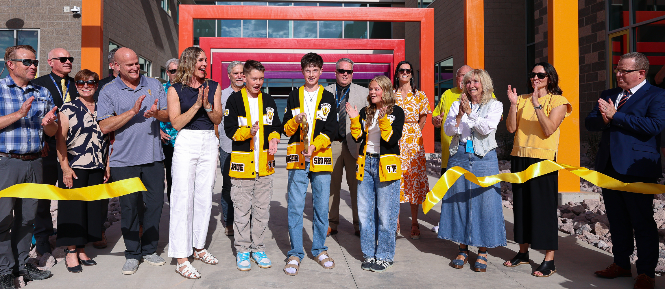 Students cutting a yellow ribbon.