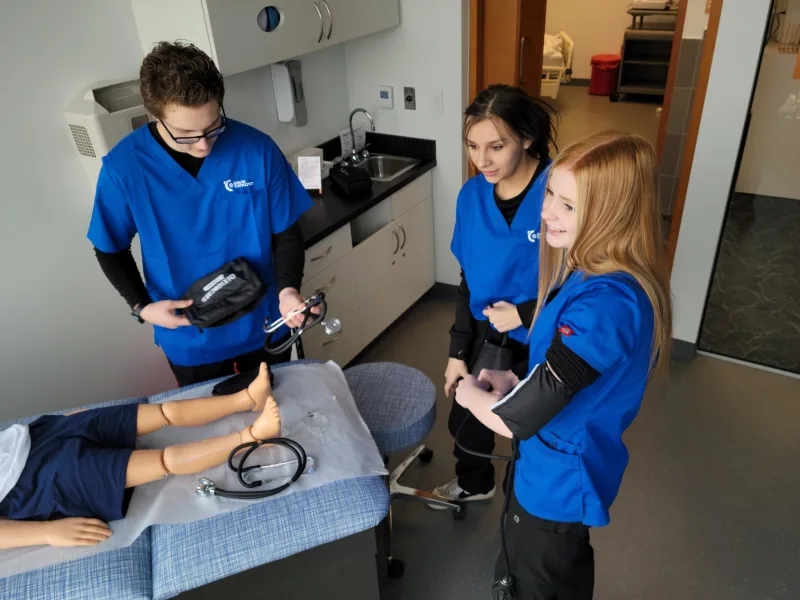 3 medical assisants students with a medical doll 