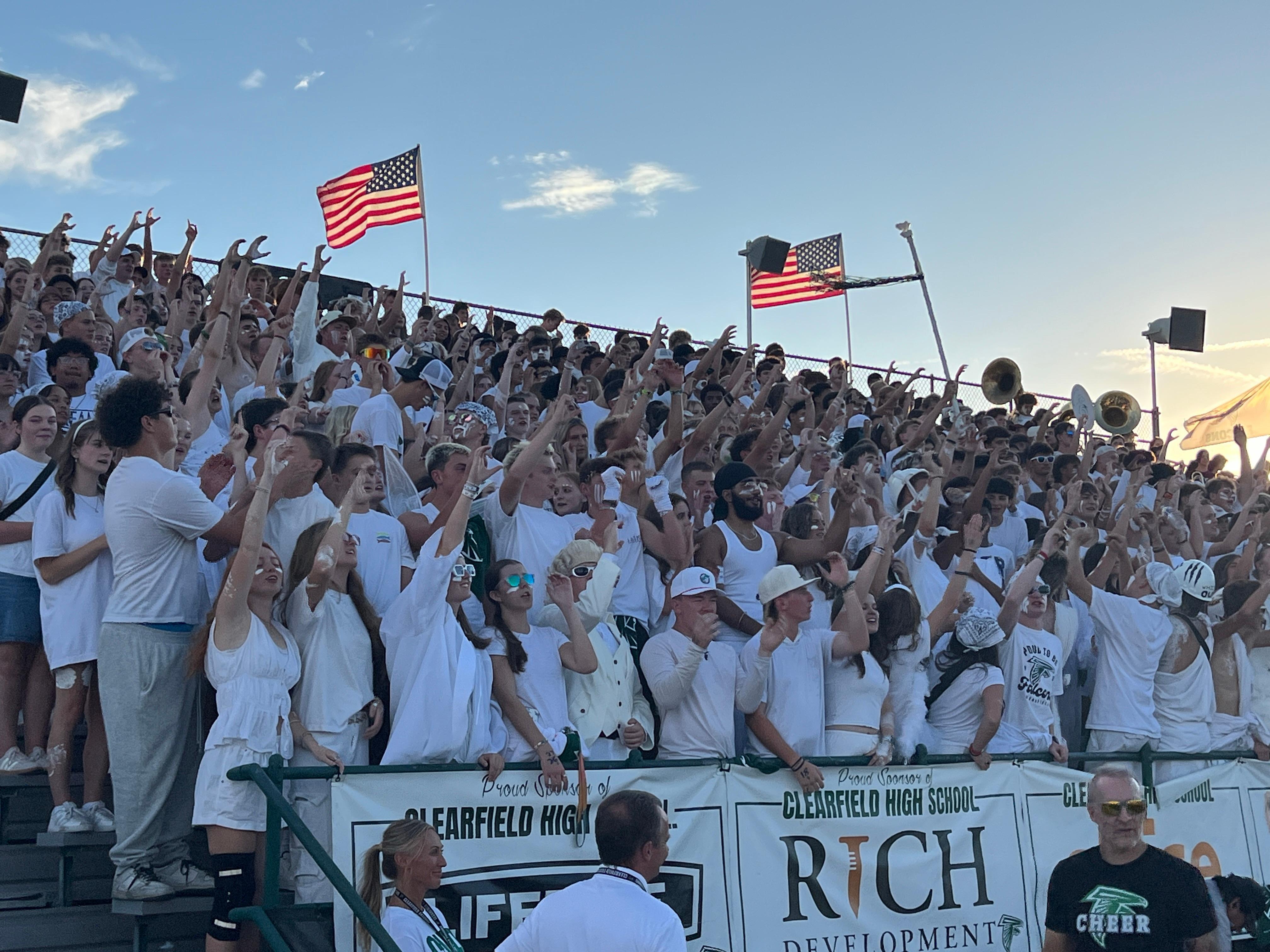 Students holding up their hands in the shape of a C for Clearfield, at a football game