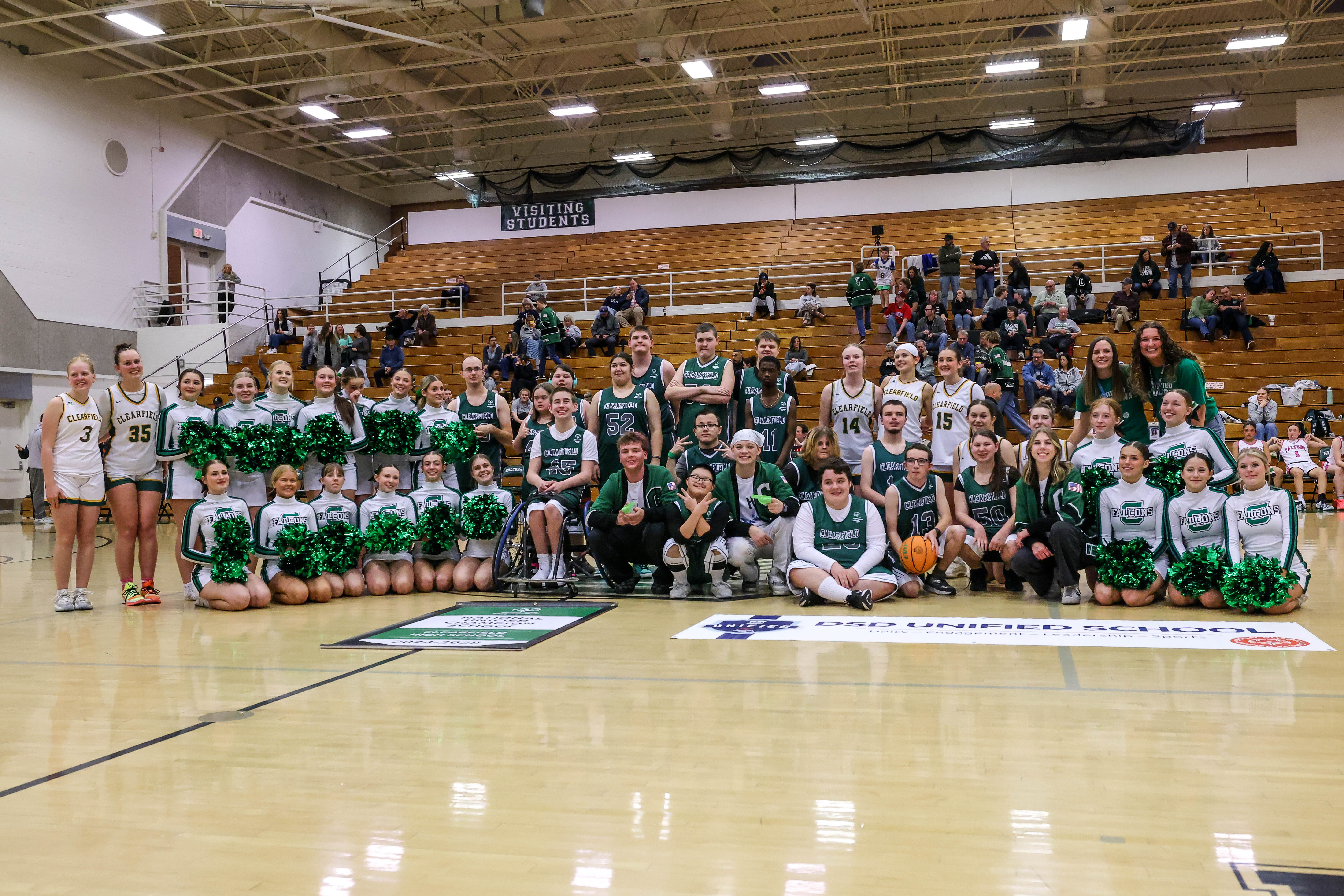 Unified sports team and other students on the basketball court receiving the Unified School Award, posing with banner