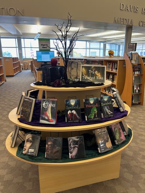 A book display with a Halloween theme, featuring books and decorations on a library shelf.