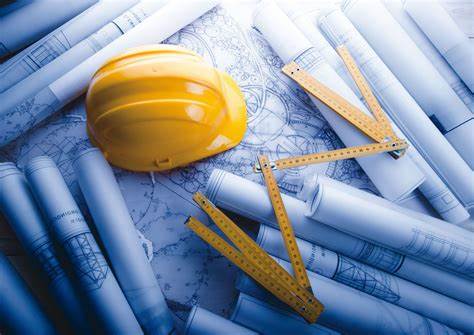 Hard hat and construction ruler lying on blueprints