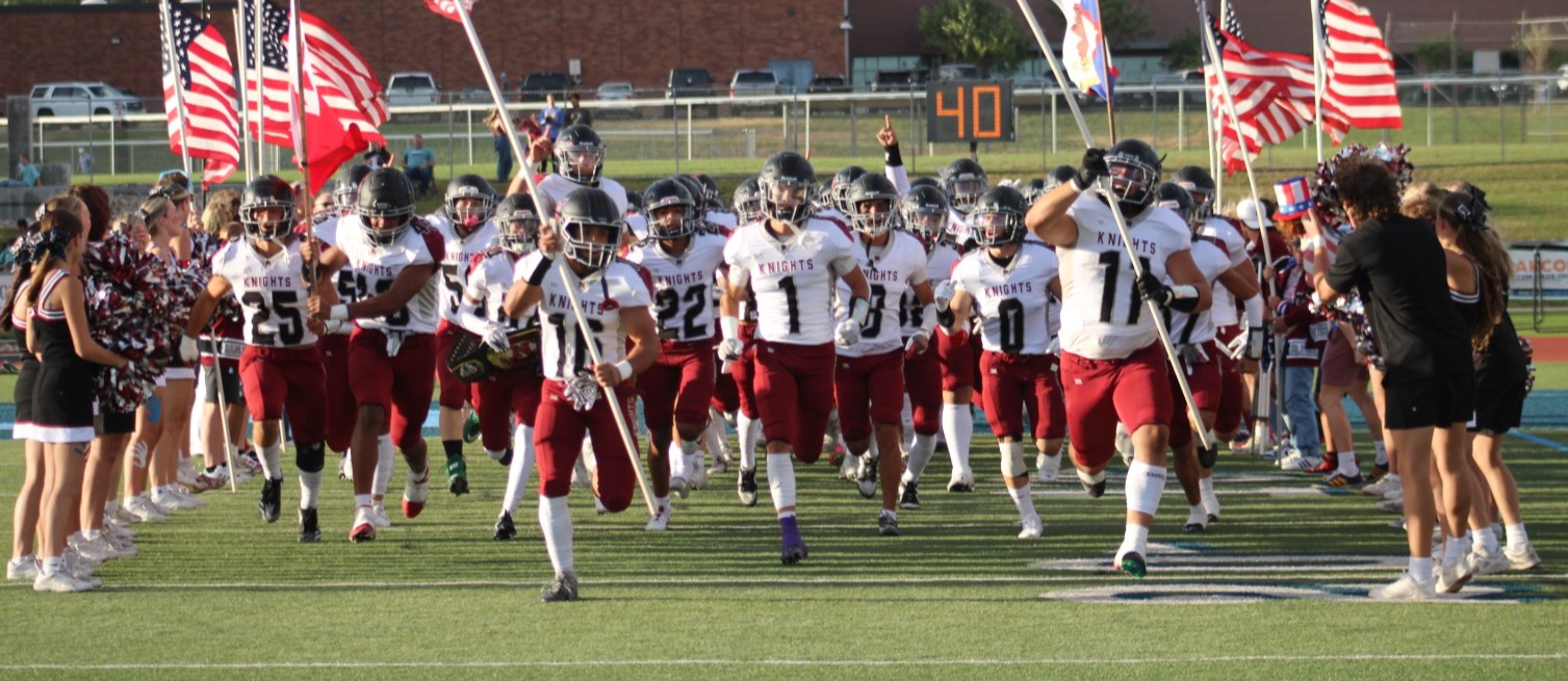 Northridge High Football team running onto the field with flags.