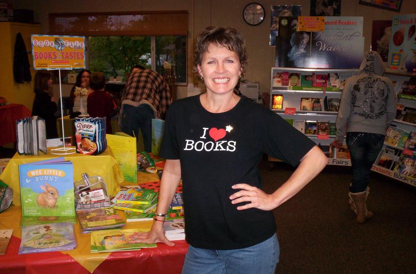 A woman standing in front of a table full of books
