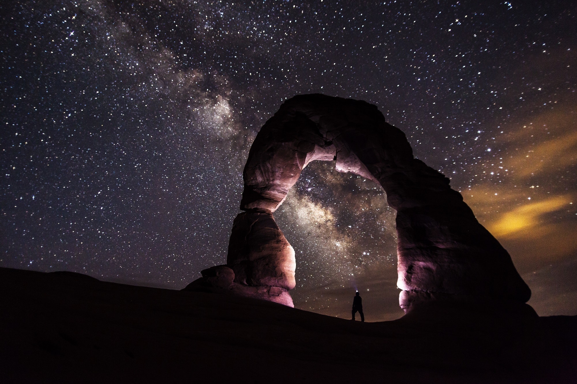A photo of an arch with a sky full with stars at the background.