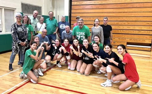 Team of young girls posing for photo with their coaches on basketball court.