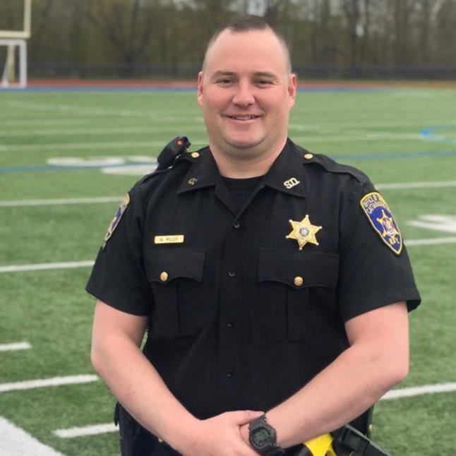 A police officer in uniform standing on a football field.
