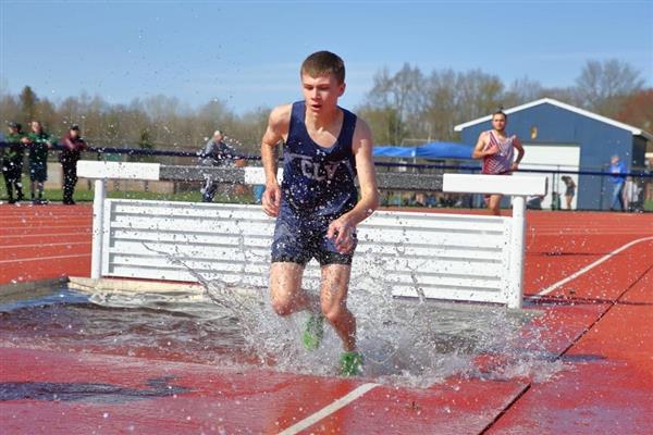 A young man running through a puddle of water