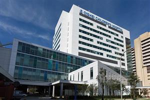 Hospital in urban setting, surrounded by cityscape buildings.