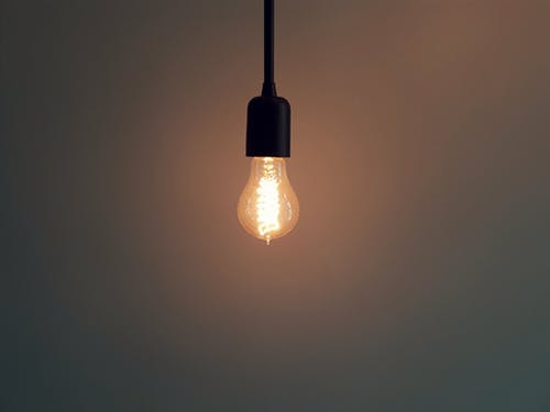 Illuminated light bulb in a dimly lit room.