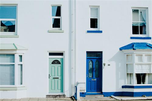 A row of white and blue houses with blue doors, creating a charming and colorful neighborhood.