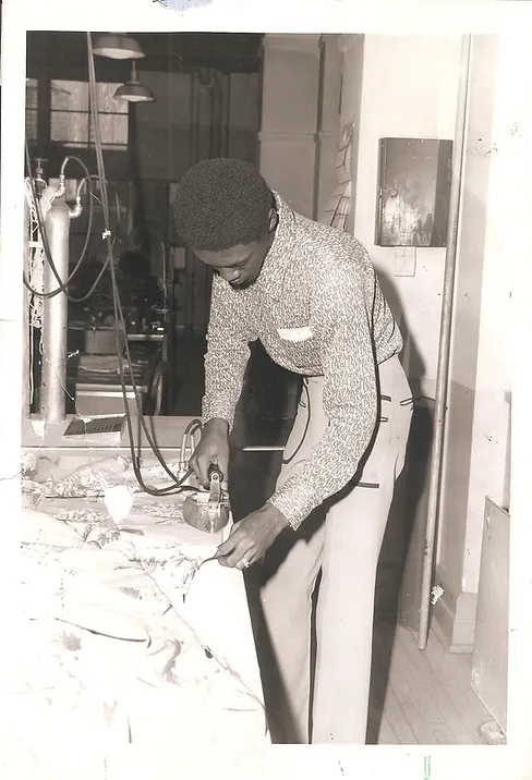 black and white 1970s photo of a young man of color ironing quilt patches