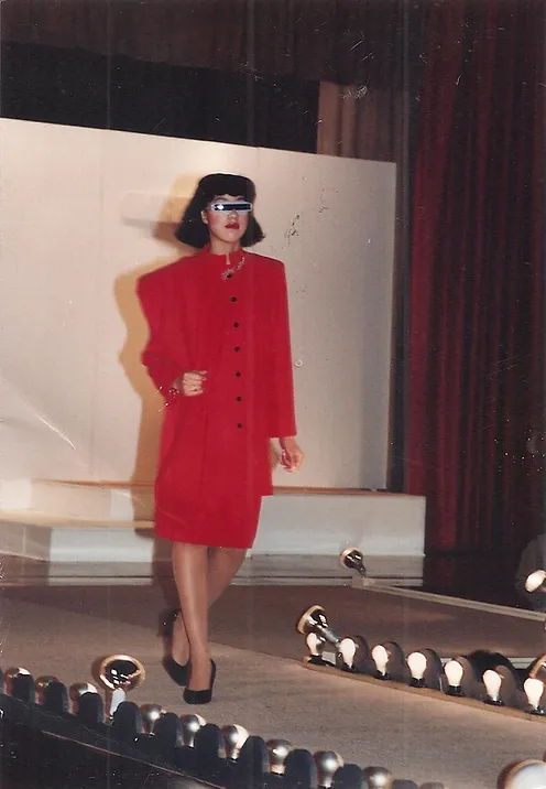model walking a catwalk in a red suit-dress and futuristic sunglasses