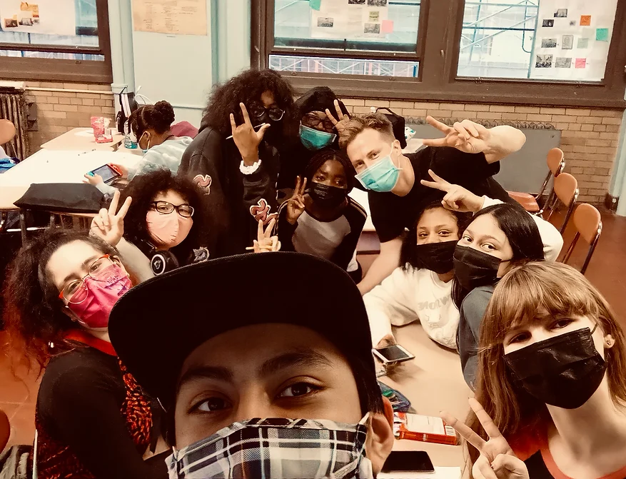 selfie of hsfi students gathered around a table wearing medical masks and holding up peace signs