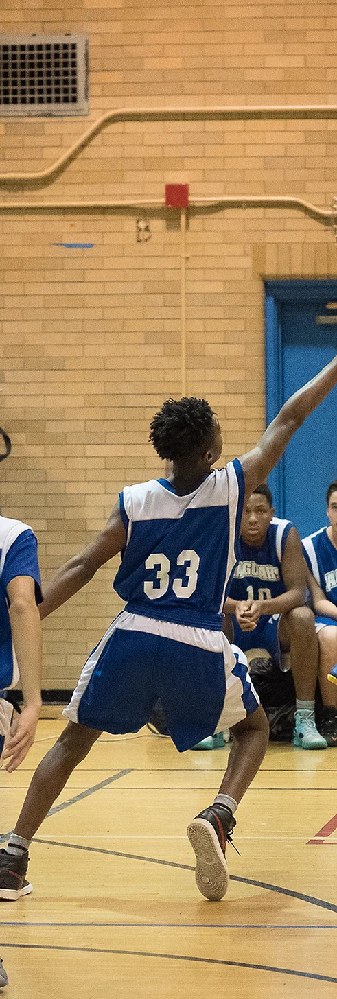 high school basketball player jumping for the ball in a blue uniform