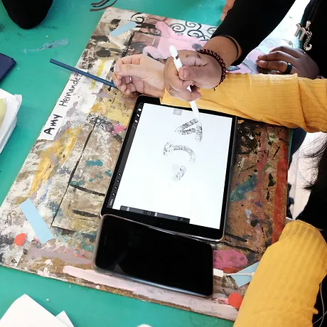 teacher reaching over the shoulder of a student drawing on an ipad