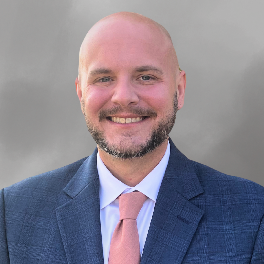 Person in a blue suit, white shirt, and pink tie
