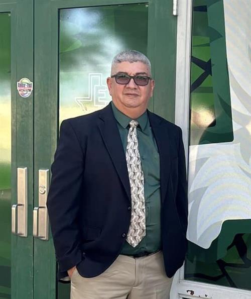 A man in a suit and tie standing in front of a green and white door.