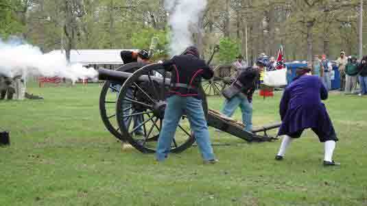 People gathered around a cannon in a park, preparing for a reenactment.