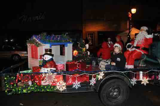 A festive holiday parade featuring a float decorated with Christmas themes, including Santa and his sleigh.