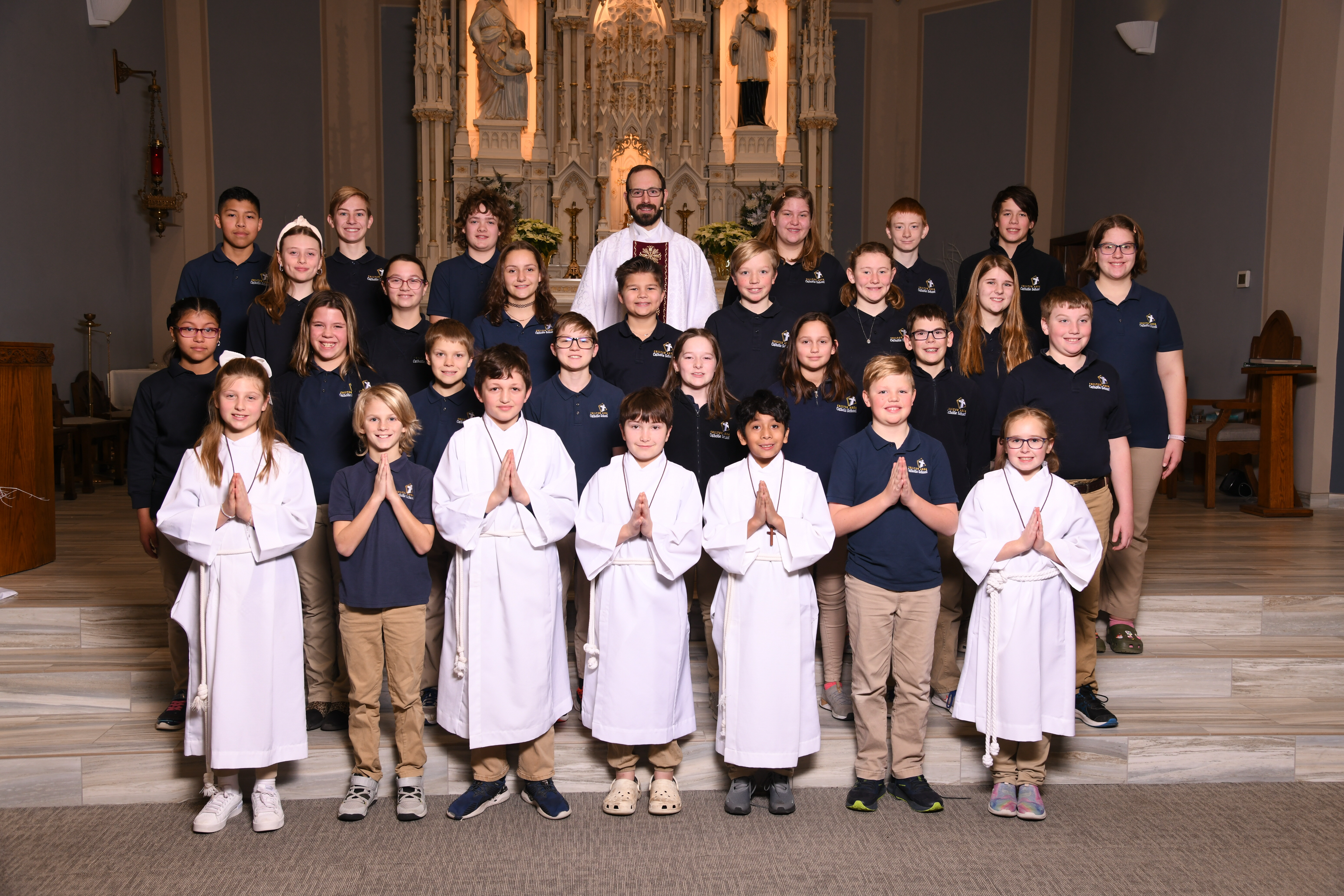 a group of students standing in front of an ornate altar inside a church.