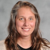 a woman wearing a patterned cardigan and a necklace