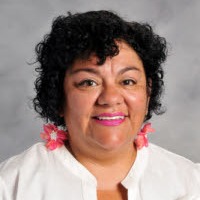 a woman with blue earrings and wearing pink blazer