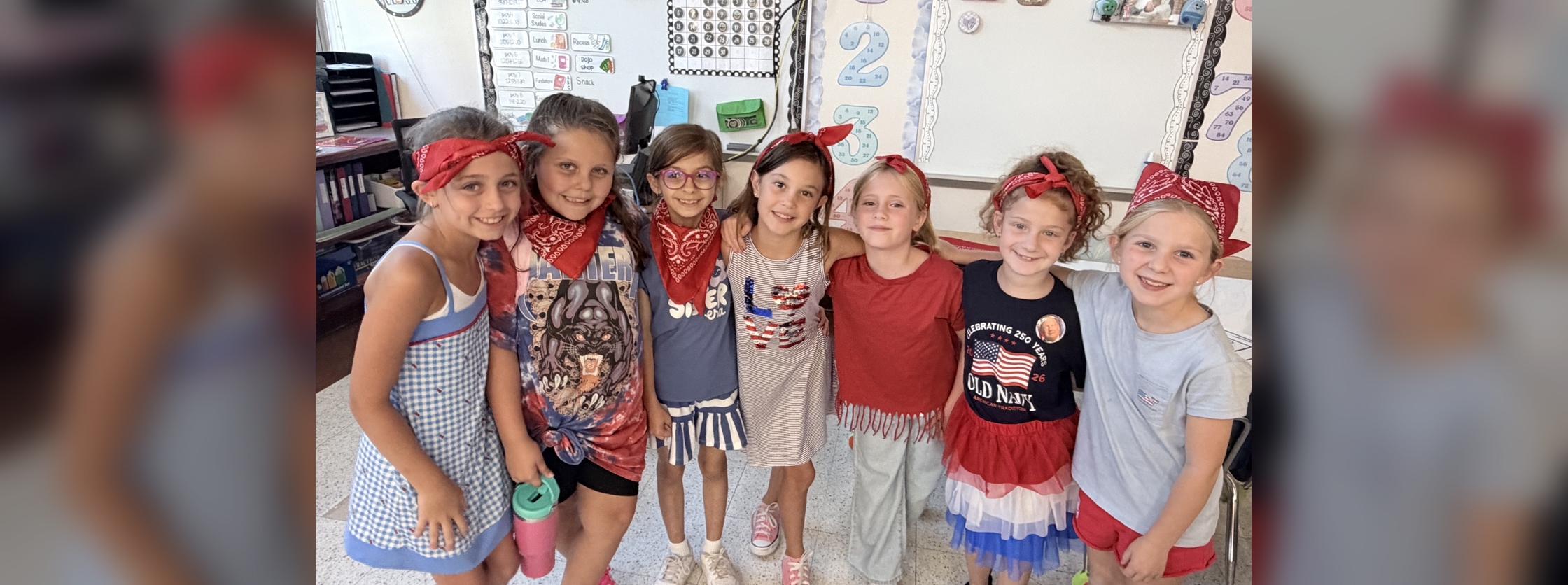 A group of people wearing red accessories poses together in a classroom setting.