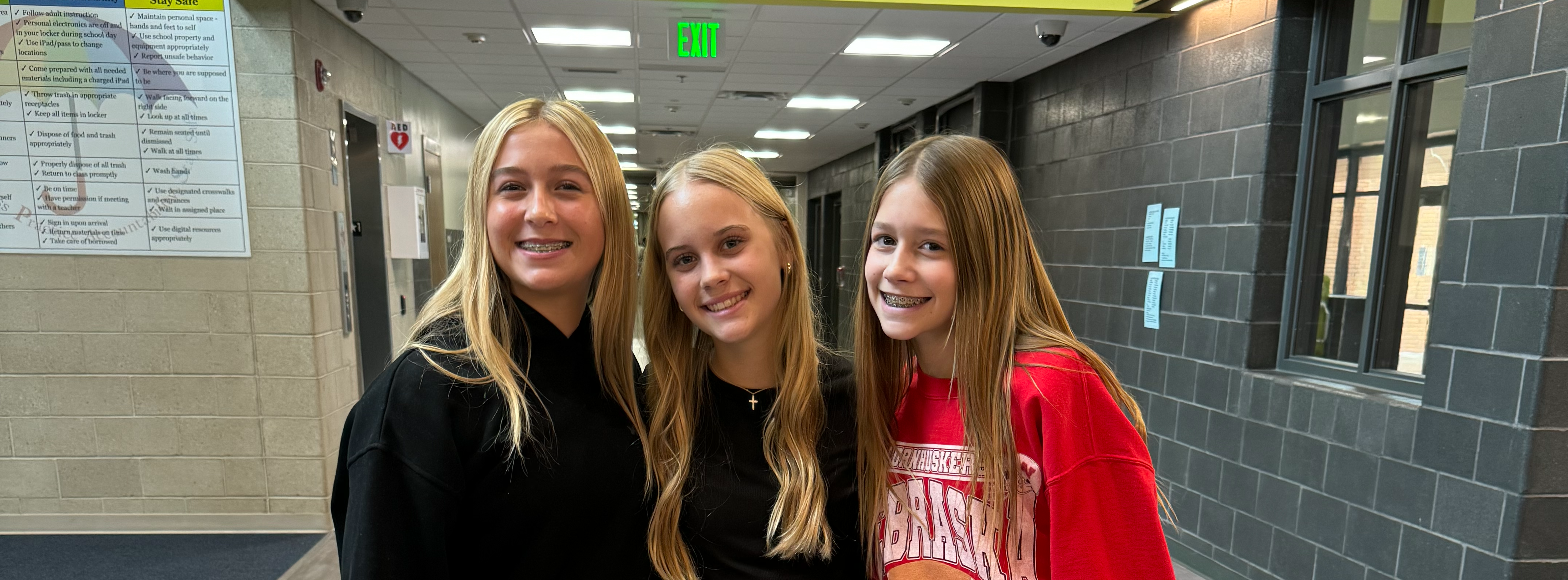 three students standing in the front hall of Aspen Middle School posing for the camera