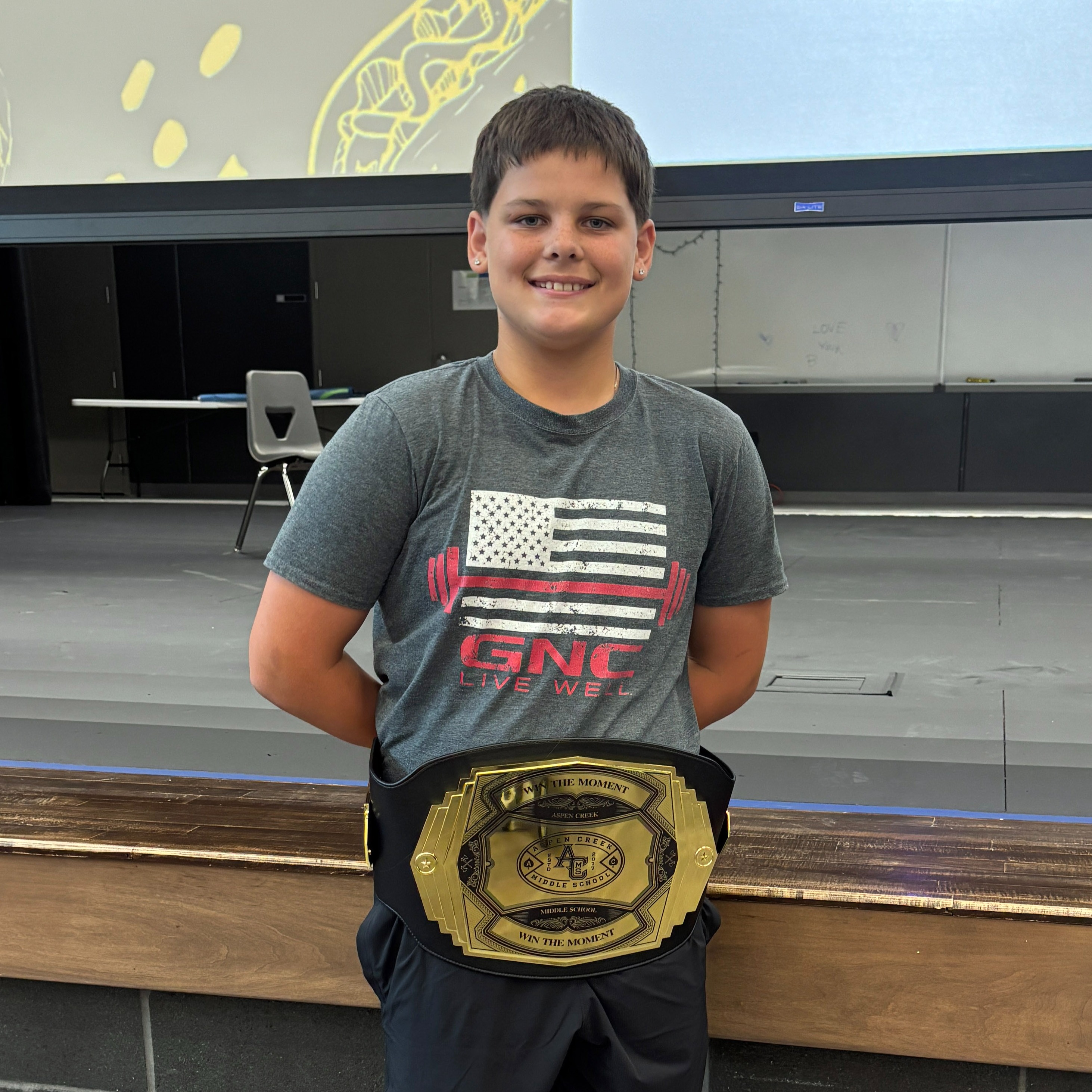 student standing in front of the state with a Win the Moment belt.