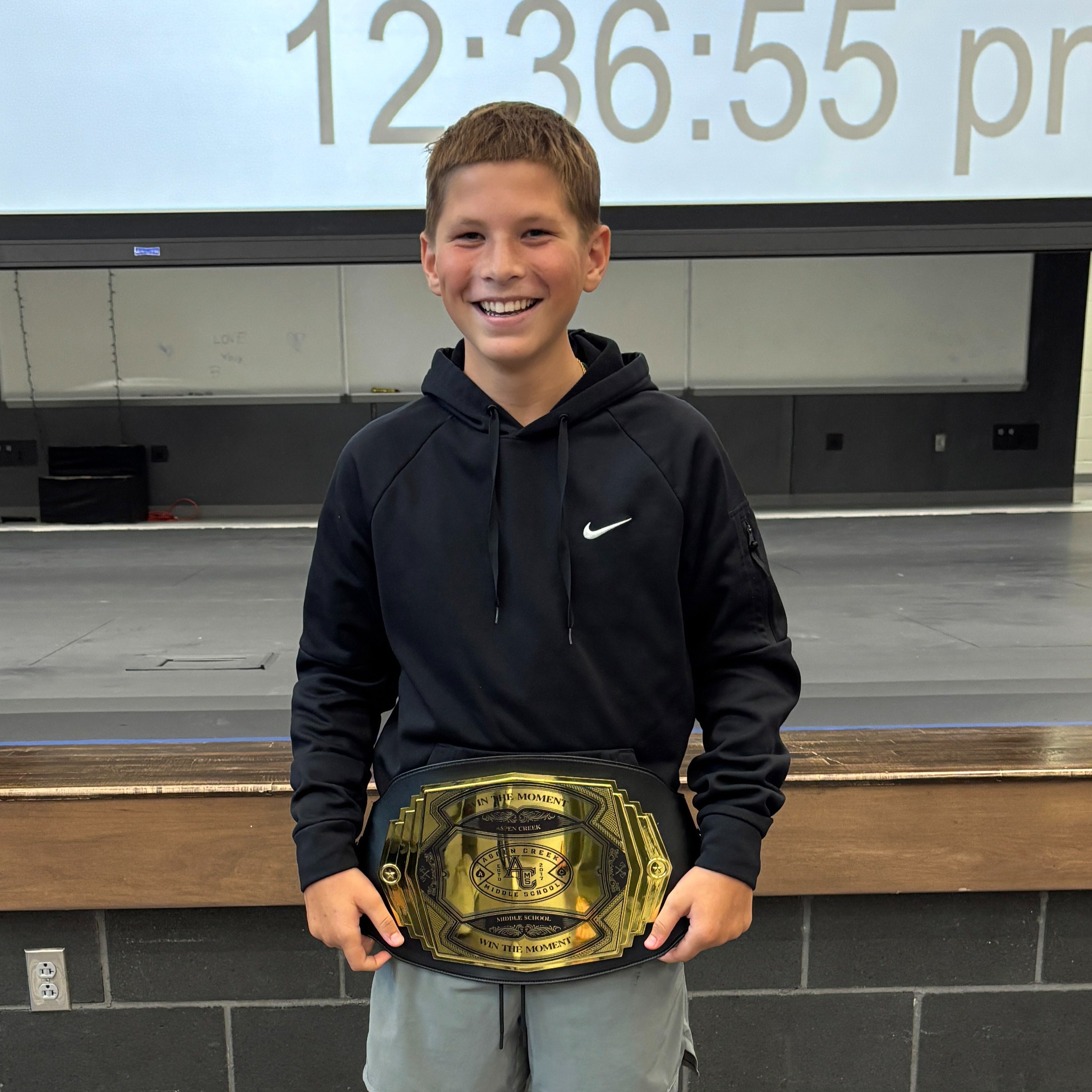 student standing in front of the state with a Win the Moment belt.