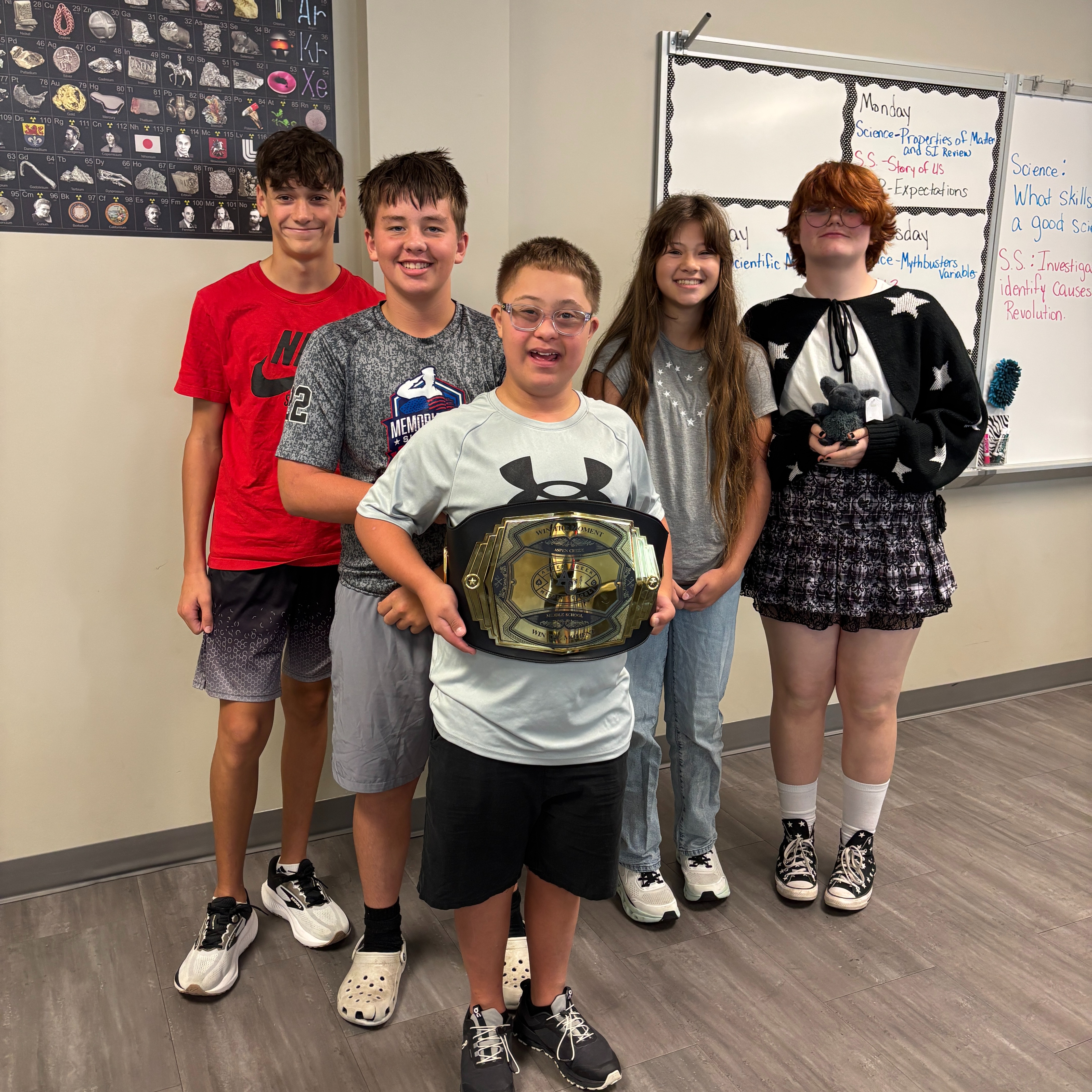 five students standing in hallway with the Win the Moment belt celebrating their outstanding leadership with kindness, accountability and safety during Character Strong