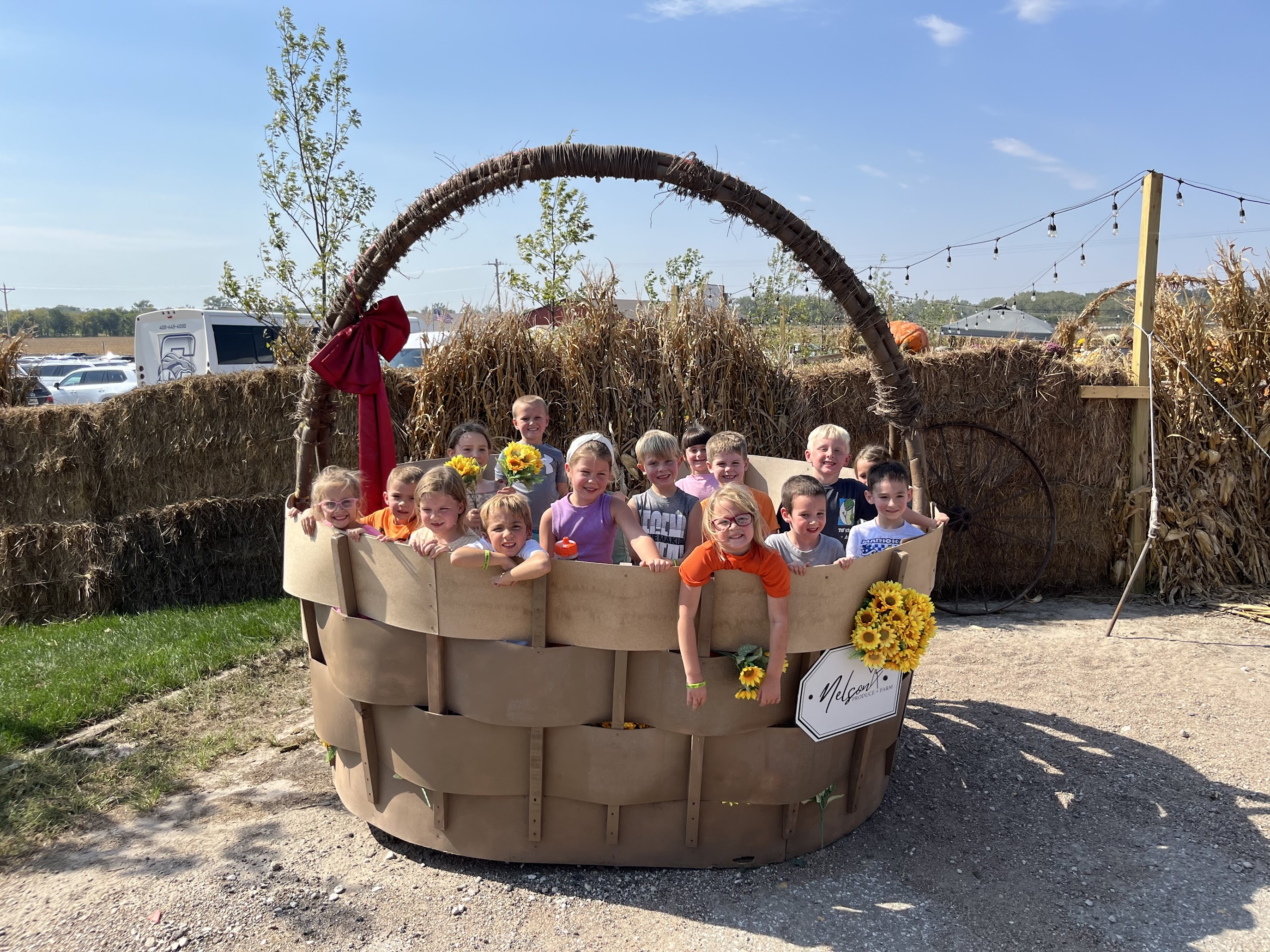 Group of students standing and smiling in a large wooden bucket.