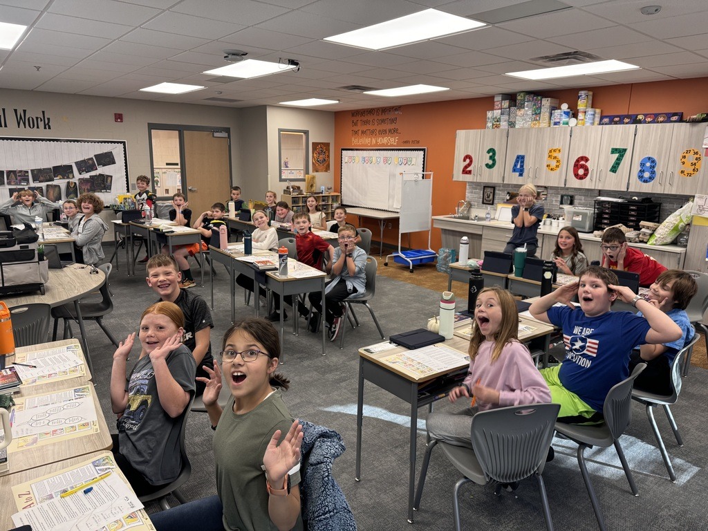 a classroom full of students at their desks making faces at the camera.