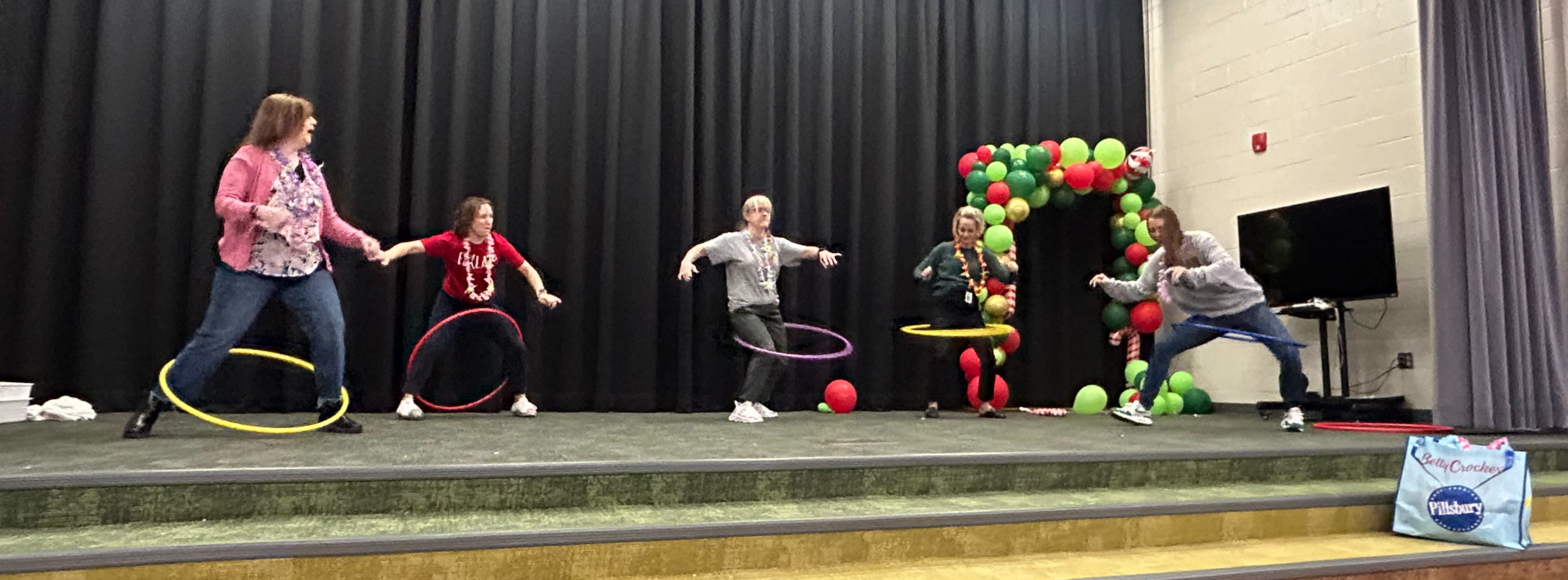 a group of teachers on the stage performing with hula hoops