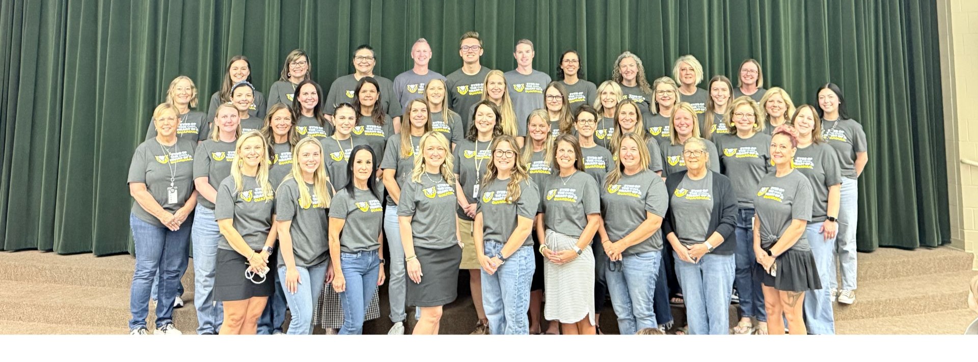 The PES staff pose for a group picture on the stage.