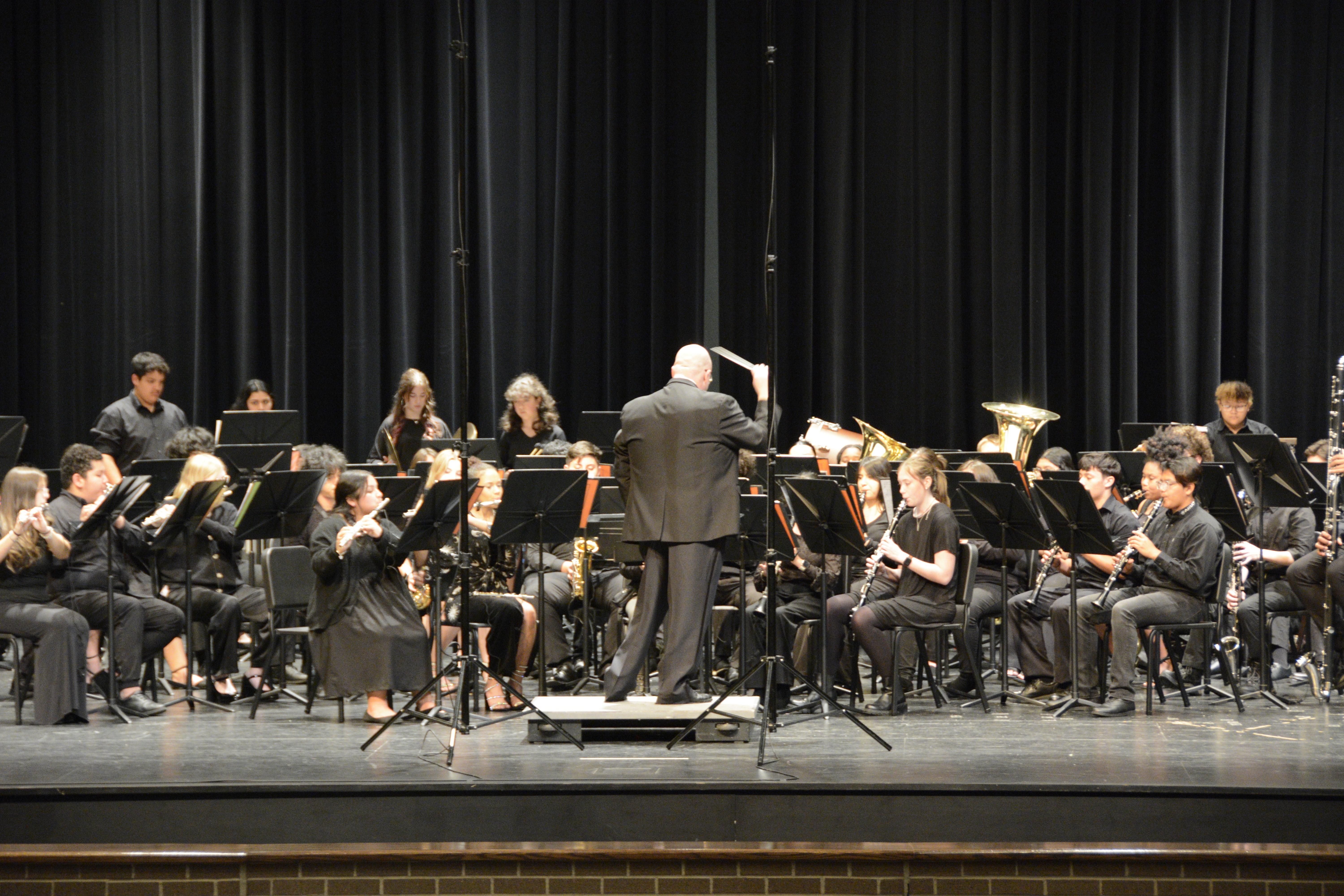 A conductor and orchestra performing on a stage