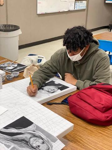 A person sitting at a table with a book and pencil