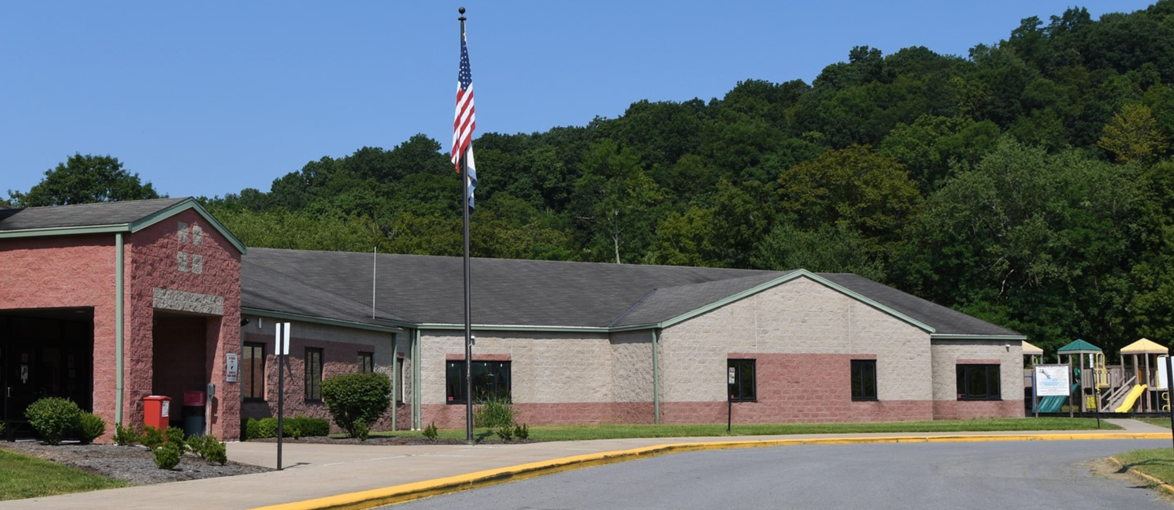 Exterior of Mason Dixon in summer Green trees, american flag on flagpole with playground in the background